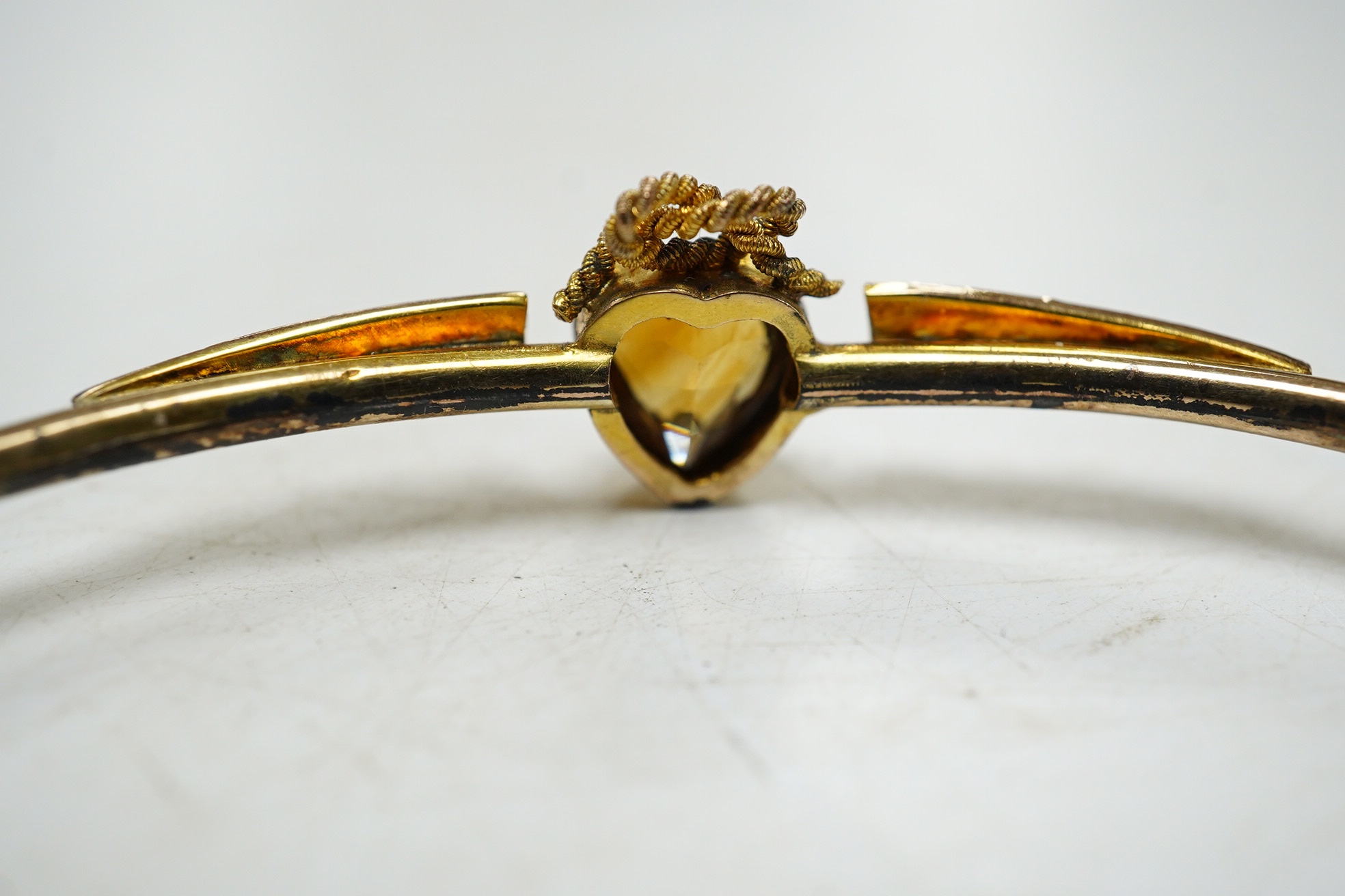 A Victorian yellow metal, citrine and seed pearl set hinged bangle, with heart shaped citrine, interior diameter 62mm, gross weight 4.6 grams, with fitted leather box. Condition - poor